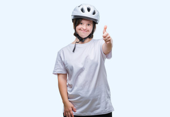 Young adult cyclist woman with down syndrome wearing safety helmet over isolated background doing happy thumbs up gesture with hand. Approving expression looking at the camera with showing success.