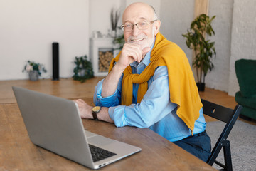 Modern technology, leisure and occupation concept. Friendly pleased mature unshaven senior male in...