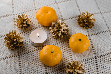 Fototapeta na wymiar Christmas composition of mandarins , golden cones and a burning decorative candle on a light background