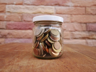 jar coins on brick wall background