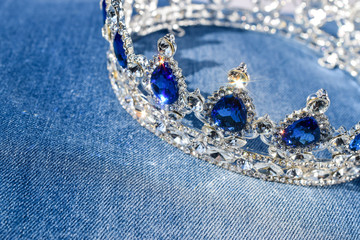 Fototapeta na wymiar Herrliche Krone mit blauen Steinen auf Blue Jeans Stoff glitzern und funkeln 