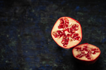 cut pomegranate fruit, two halves, on a dark background, top view