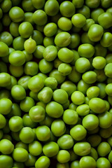 Beans and pods of green peas lie on a large number of other peas.