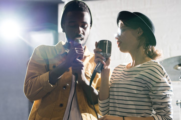 Waist up portrait of contemporary young couple singing on stage enjoying performance together