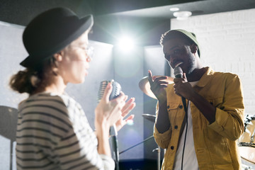 Waist up portrait of contemporary young couple singing on stage looking at each other and  enjoying performance