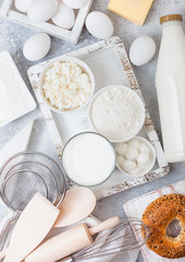Fresh dairy products on white table background. Glass of milk, bowl of flour and cottage cheese and eggs. Box of baking utensils. whisk and spatula in vintage wooden box.Top view. Fresh bagel