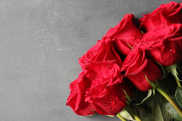 Bouquet of red roses with dew drops on a gray wooden background close-up. Copy space.