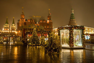 Fototapeta na wymiar Moscow, Russia. Beautiful Decorated Christmas Trees At Manege Square, On Background Lverskaya Chapel, State Historical Museum And Moscow Kremlin In Evening At Winter.