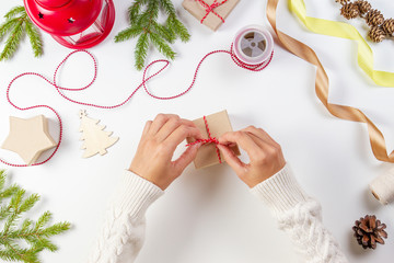 Christmas gift wrapping. Woman's hands packing Christmas presents on white table