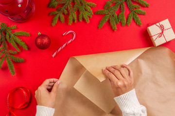 Christmas gift wrapping. Woman's hands packing Christmas present box in craft paper