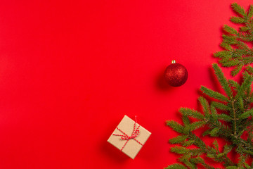 Christmas composition. Fir tree branches, christmas decorations and present gift box on red background