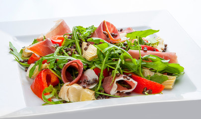 Salad with prosciutto and artichokes on a white plate