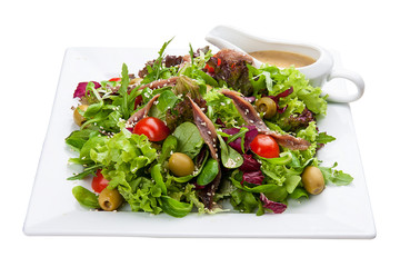 Salad with anchovies and vegetables on a white plate