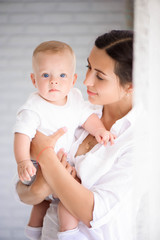 Mother and child in a white room. Mom and baby boy in diaper pla