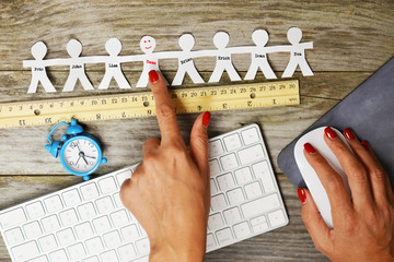 Time to evaluate employee performance concept with human silhouettes, wooden ruler and alarm clock
