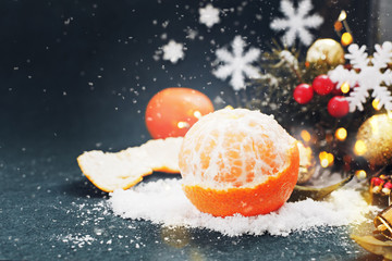 Fototapeta na wymiar Tangerine with snow in Christmas decor on the dark blue background. Christmas or New Year concept. Copy space.