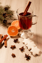 Glass of Christmas mulled wine with spices, orange and cookies on wooden boards