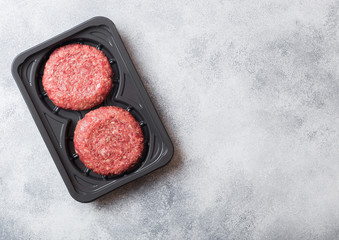 Plastic tray with raw minced home made grill beef burgers with spices and herbs. Top view.