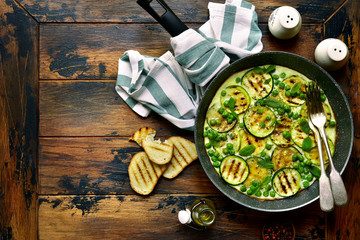 Omelette with grilled zucchini slices, sweet pea and mint.Top view with copy space.