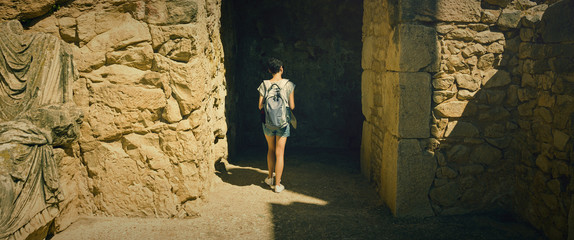 A girl with a backpack walks along the ruins in the city of Dougga. Tunisia, travel.
