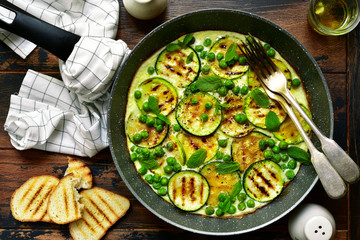 Omelette with grilled zucchini slices, sweet pea and mint.Top view with copy space.