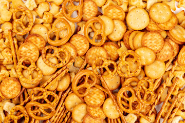 A photo of an assortment of salt crackers, sticks, pretzels, and fishes, shot from above on a white background