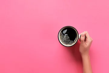 Kissenbezug Minimalistic style woman hand holding a cup of coffee on pink background. Flat lay, top view © sosiukin