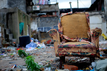 Daytime close-up of an old and worn-out armchair thrown into the street and all around urban waste in Shanghai, China
