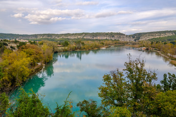 Fototapeta na wymiar Vue panoramique sur le village de Quinson et le lac en automne. Ciel nuageux. Alpes de Haute Provence, France. 
