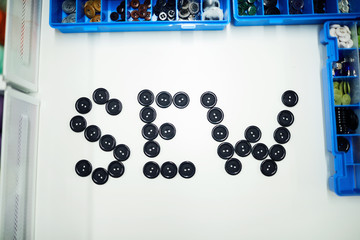 Top view of SEW word made of black buttons on table in tailoring studio, background shot