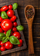 Organic Tomatoes with basil and pepper on spoon in vintage wooden box on wooden kitchen table