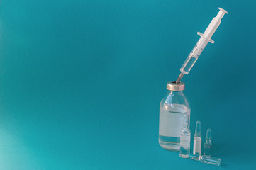syringe with a vaccine in a glass bottle on a blue background, close-up