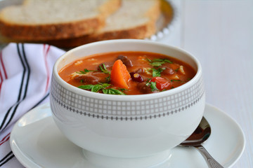 Minestrone soup with beans and vegetables in porcelain bowl