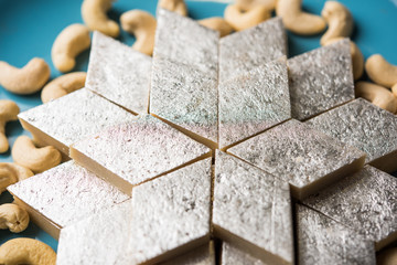 Kaju Katli is a Diamond shape Indian sweet made using cashew sugar and mava, served in a plate or bowl over moody background. selective focus