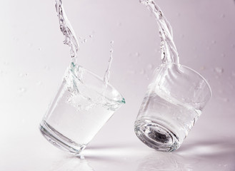 Glasses of water falling and jumping with splashes and drops	