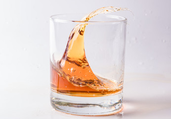 A shattering glass of brandy or brandy. Shards of glass and splashes of drink