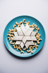Kaju Katli is a Diamond shape Indian sweet made using cashew sugar and mava, served in a plate or bowl over moody background. selective focus
