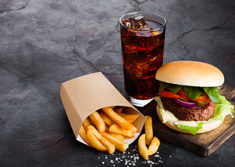 Fresh beef burger with sauce and vegetables and glass of cola soft drink with potato chips fries on...