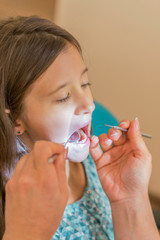 Little girl at the reception in the dentist's office. little girl sitting in a chair near a dentist after dental treatment. Little girl sitts in the dentist's office. vertical photo