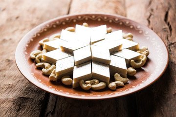Kaju Katli is a Diamond shape Indian sweet made using cashew sugar and mava, served in a plate or bowl over moody background. selective focus