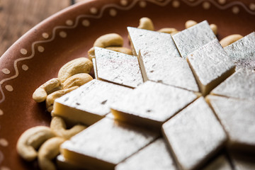 Kaju Katli is a Diamond shape Indian sweet made using cashew sugar and mava, served in a plate or bowl over moody background. selective focus