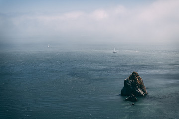 Foggy sea with rock sticking out of water