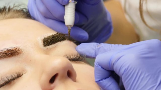 close-up hands of the master doing brows tattoo. professional eyebrow permanent makeup. 4K