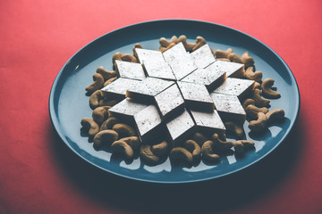 Kaju Katli is a Diamond shape Indian sweet made using cashew sugar and mava, served in a plate or bowl over moody background. selective focus