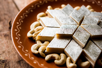 Kaju Katli is a Diamond shape Indian sweet made using cashew sugar and mava, served in a plate or bowl over moody background. selective focus