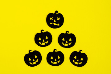 Holiday decorations for Halloween. Black paper pumpkins on a yellow background, top view.