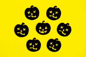 Holiday decorations for Halloween. Black paper pumpkins on a yellow background, top view.