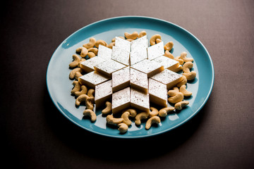 Kaju Katli is a Diamond shape Indian sweet made using cashew sugar and mava, served in a plate or bowl over moody background. selective focus