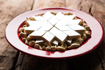 Kaju Katli is a Diamond shape Indian sweet made using cashew sugar and mava, served in a plate or bowl over moody background. selective focus