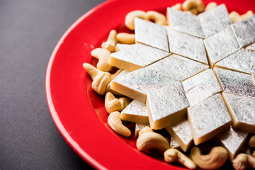 Kaju Katli is a Diamond shape Indian sweet made using cashew sugar and mava, served in a plate or bowl over moody background. selective focus